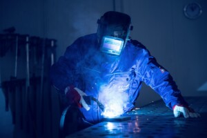 Mitarbeiter schweißt Metall in der Werkstatt.