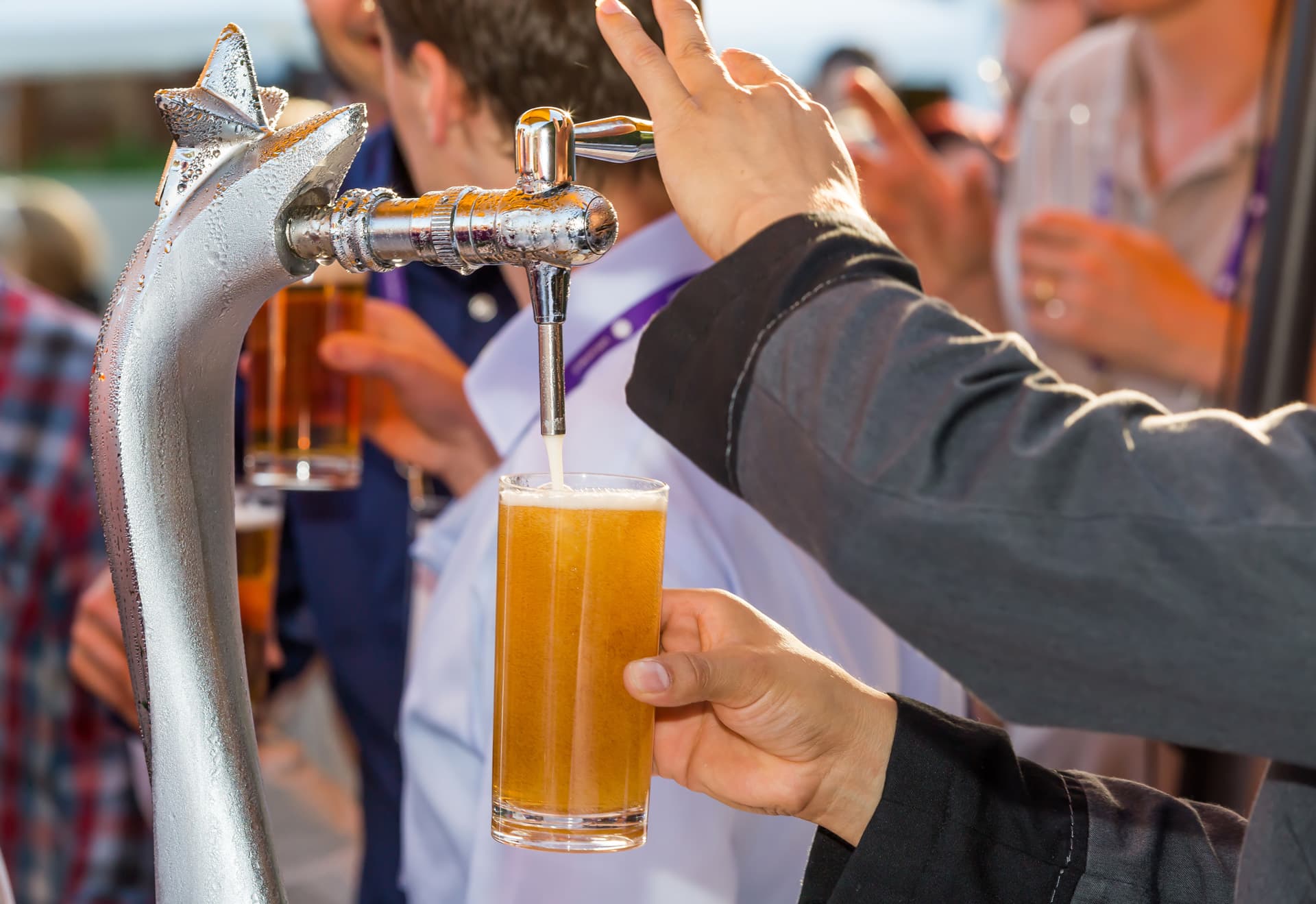 Eine Person zapft frisch gezapftes Bier aus einer Zapfanlage in ein Glas.