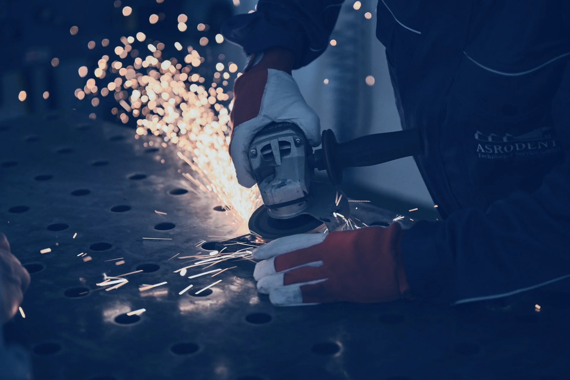 Ein Mitarbeiter schleift Metall in der Werkstatt.