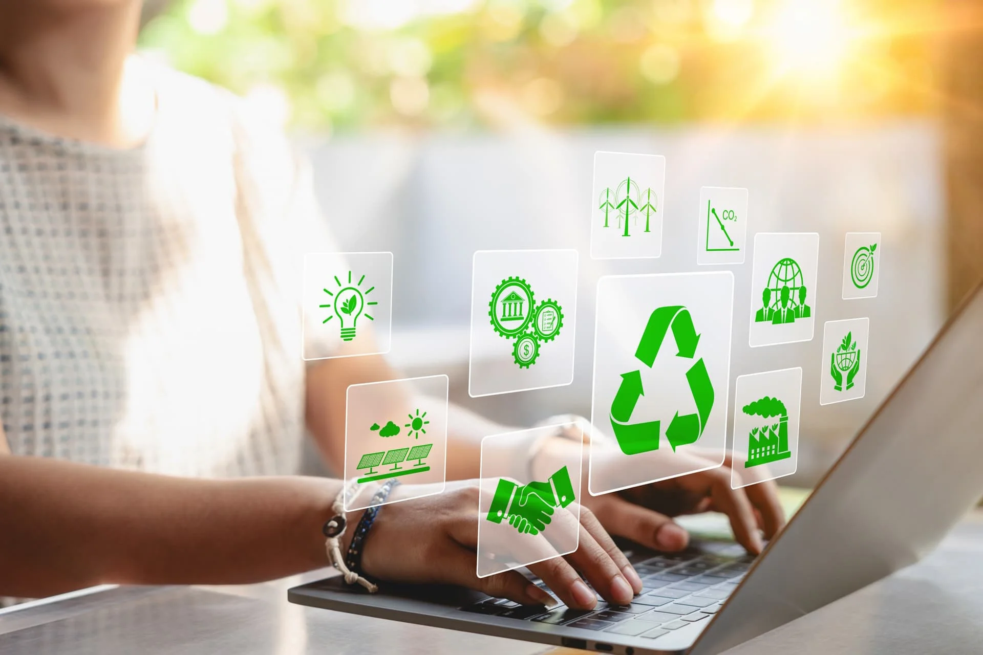 Eine Frau benutzt einen Laptop mit virtuellen Symbolen zu Recycling, erneuerbaren Energien und Umweltschutz.